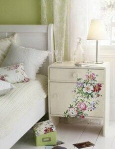 Painted nightstand in a shabby chic bedroom with lacy curtains.