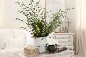 An all white shabby chic living room with greenery on the coffee table.